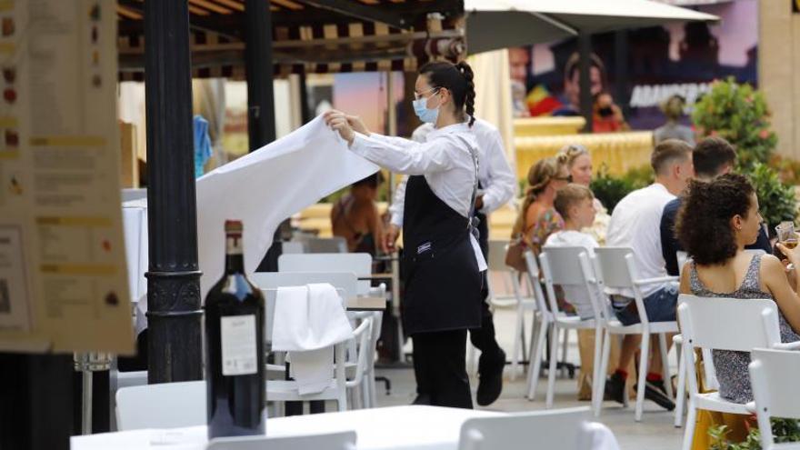 Una camarera prepara una mesa en una terraza de Murcia.