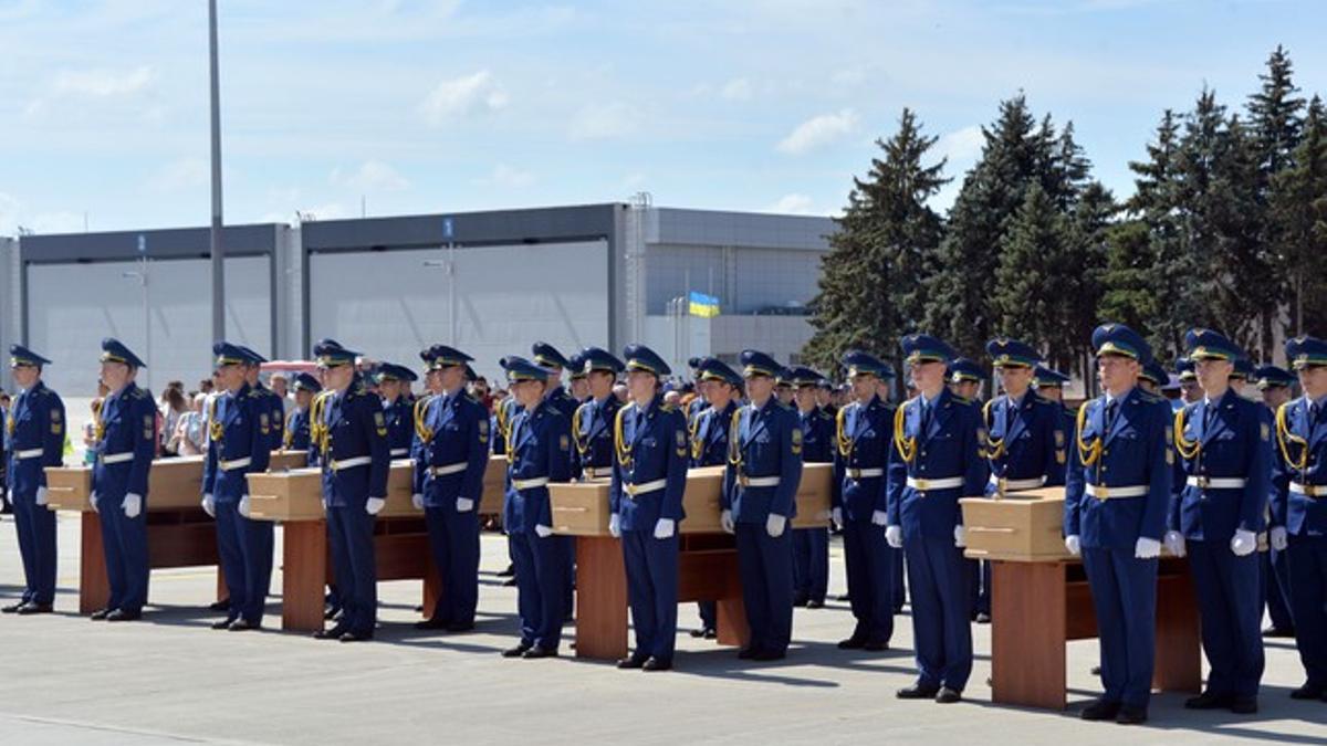 Soldados ucranianos cargan ataúdes de las víctimas del vuelo MH-17 antes de subirlos al avión rumbo a Holanda, este miércoles en Járkov.