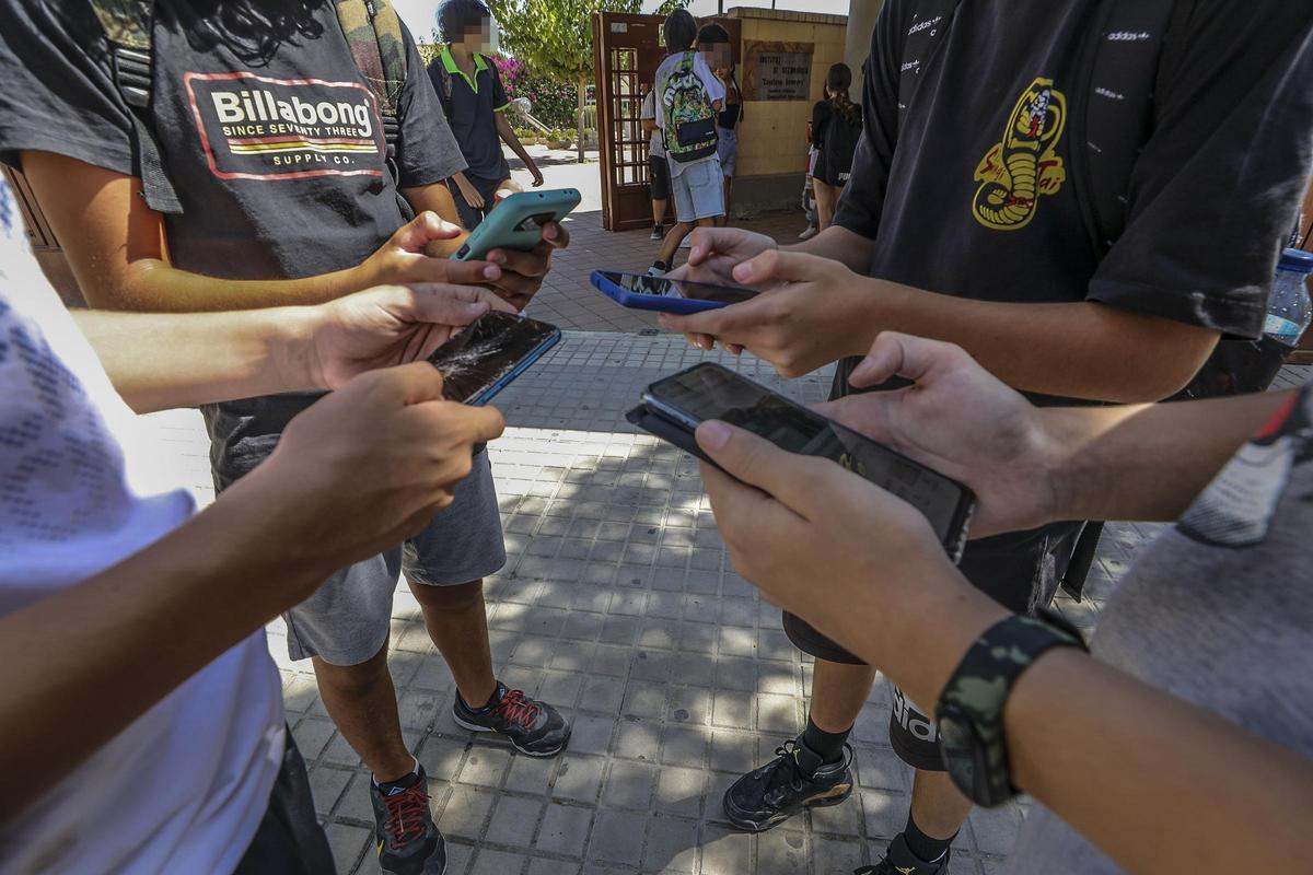 Alumnos con sus móviles a las puertas de un instituto de Elche