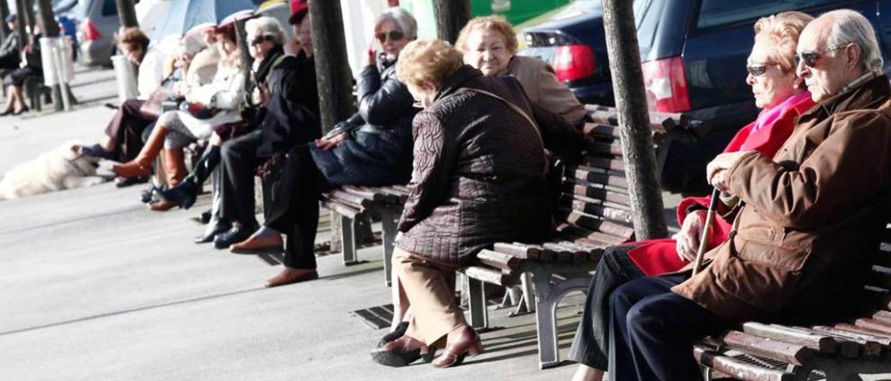 Personas mayores tomando el sol en el puerto deportivo de Gijón.