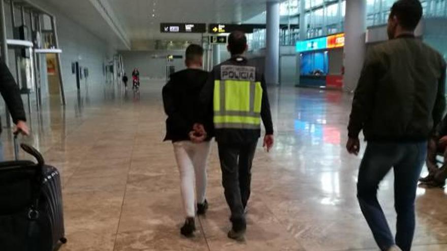 Un policía traslada al detenido en el aeropuerto.