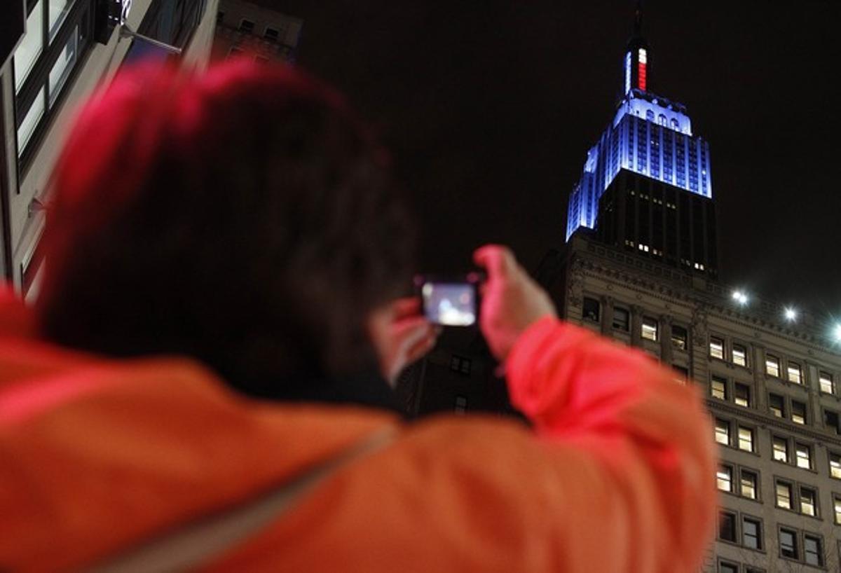 Una dona fa una foto de l’Empire State, il·luminat de color blau, en honor a Obama, guanyador de les eleccions.