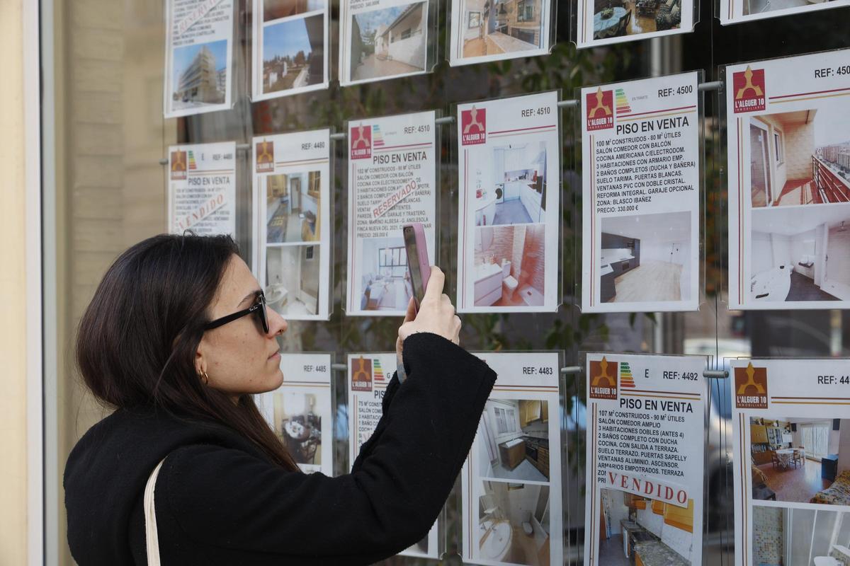 Una joven fotografia un anuncio de una inmobiliaria valenciana.