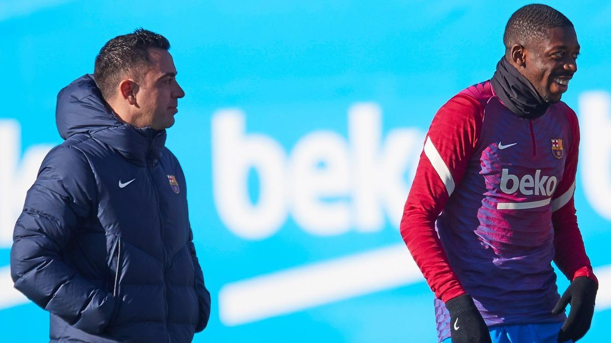 El entrenador del FC Barcelona, Xavi Hernández, junto al delantero francés Ousmane Dembélé (d), durante el entrenamiento que el equipo azulgrana ha realizado en la ciudad deportiva Joan Gamper para preparar el partido que mañana disputará ante el Betis.
