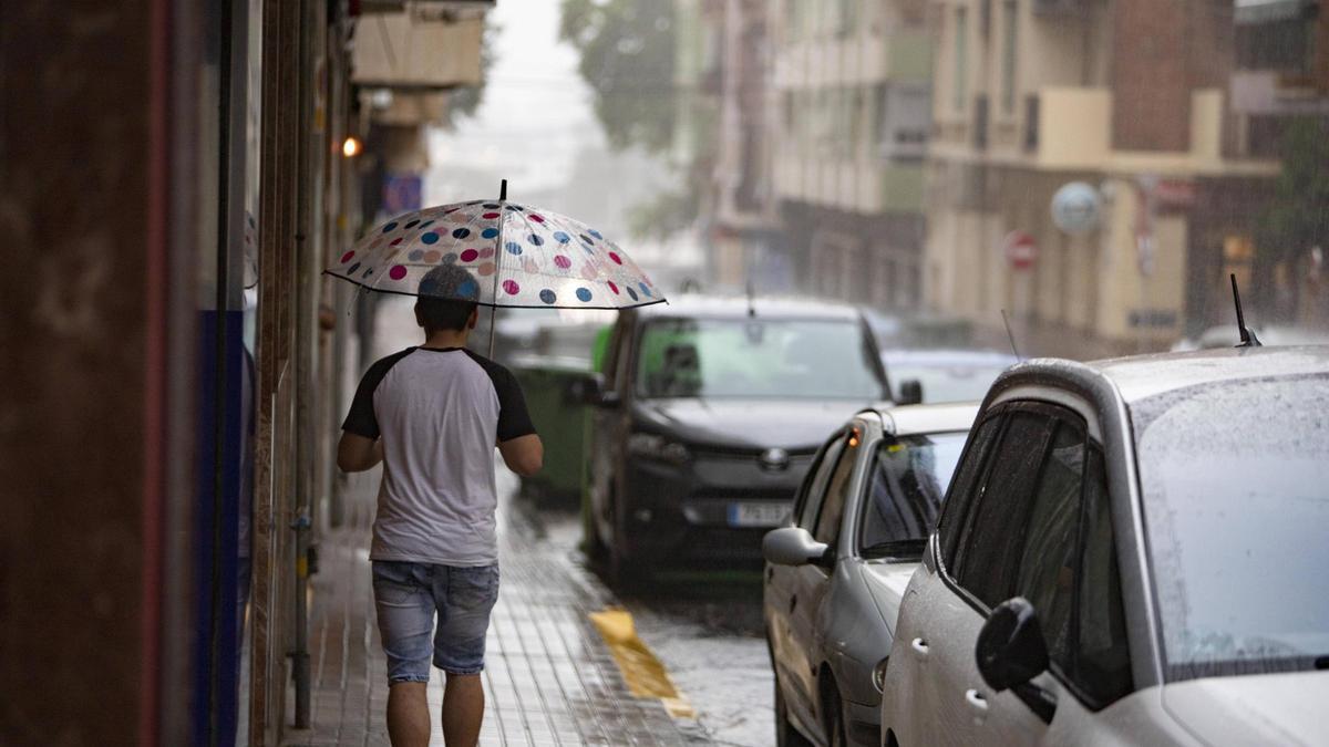 Un vecino pasea con un paraguas por Xàtiva en medio de una tormenta de verano.