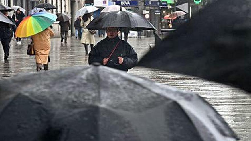 Peatones se protegen de la lluvia con sus paraguas en los Cantones de A Coruña.