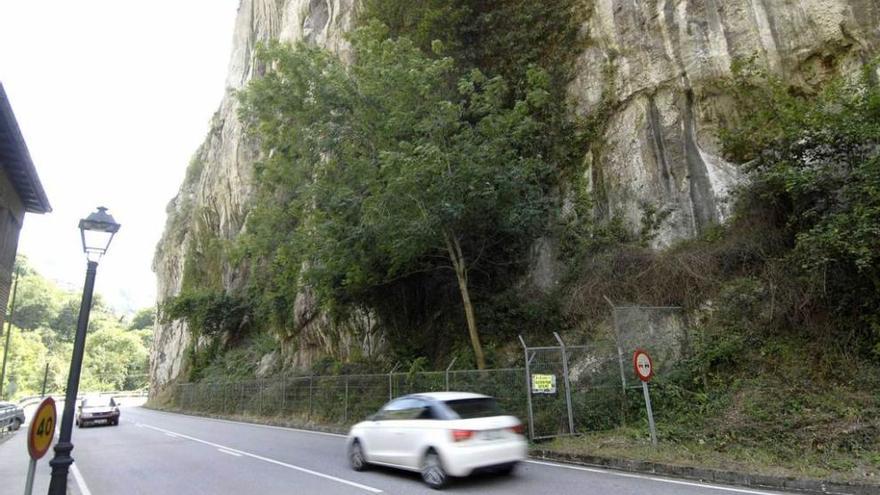 Tráfico en el entorno de la cueva, protegida por una verja metálica.