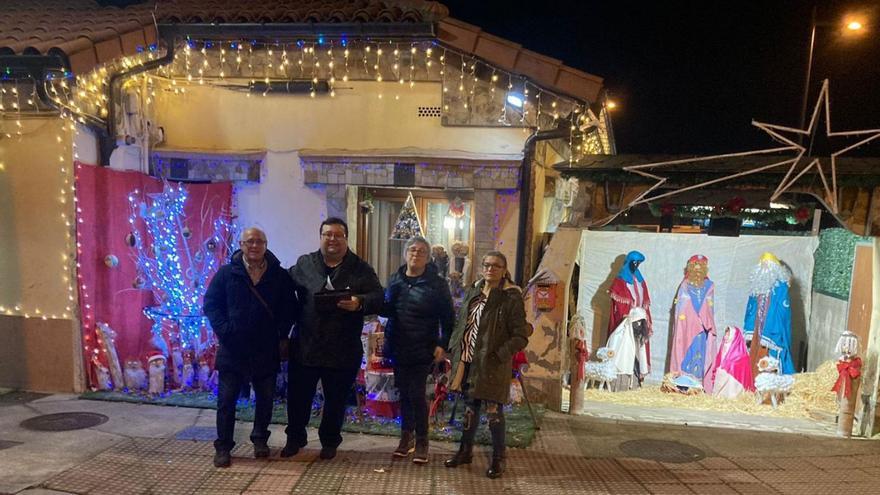 El edil Luis Pacho, segundo por la izquierda, posa junto a varios vecinos delante de la vivienda ganadora del concurso de decoración navideña.