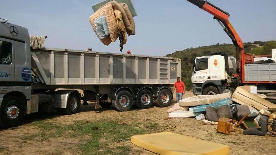 Colchones son arrojados a uno de los dos camiones bañera alquilados.