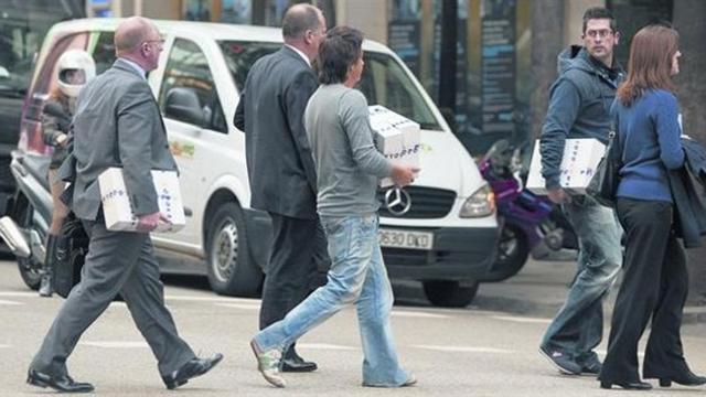 Agentes de Scotland Yard y de la Policía Nacional cargan con cajas de documentos cedidos por la agencia de detectives, ayer en Barcelona.
