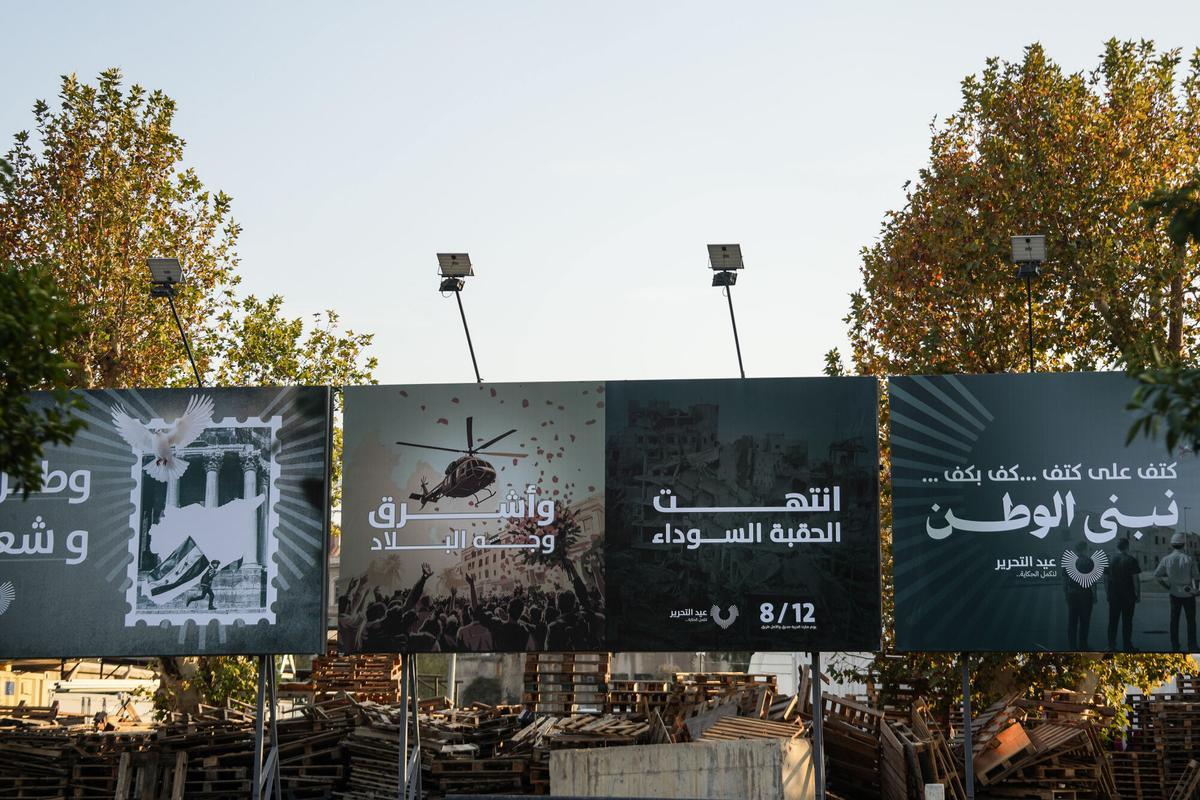 Carteles en los que se puede leer 'La era negra ha acabado y el rostro del país ha empezado a brillar", en Damasco, con motivo del primer aniversario de la caída del régimen de los Asad.
