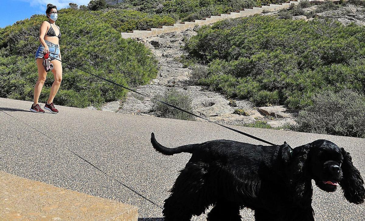 Una joven saca a pasear a su perro en las inmediaciones del faro de Cabo de Palos. | JUAN CABALLERO