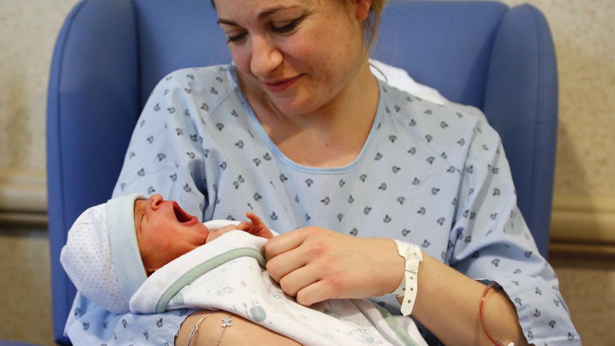 Tierno gesto de Alejandro, ante la mirada de su madre, instantes después de nacer en el hospital San Juan de Dios.