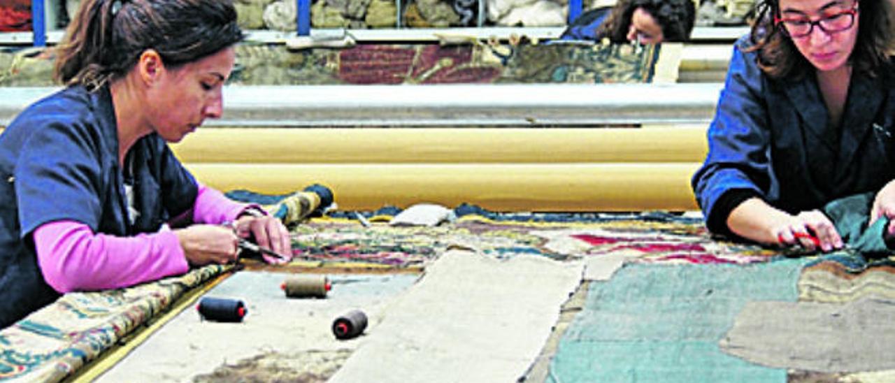 Soledad María, a la izquierda, y Sofía Fernández trabajan en la recuperación de un tapiz de la catedral de Sigüenza en el taller de restauración de tapices históricos.