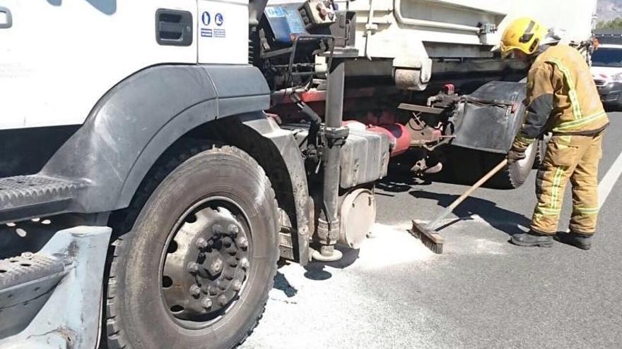 Bomberos trabajando en la limpieza de la calzada junto al camión que se ha incendiado en la autovía.