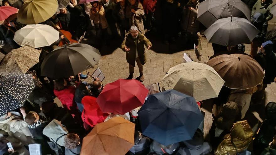 Pablo Costas, dirigiendo a un coro que se cubría con paraguas de la lluvia en la Praza do Arco.