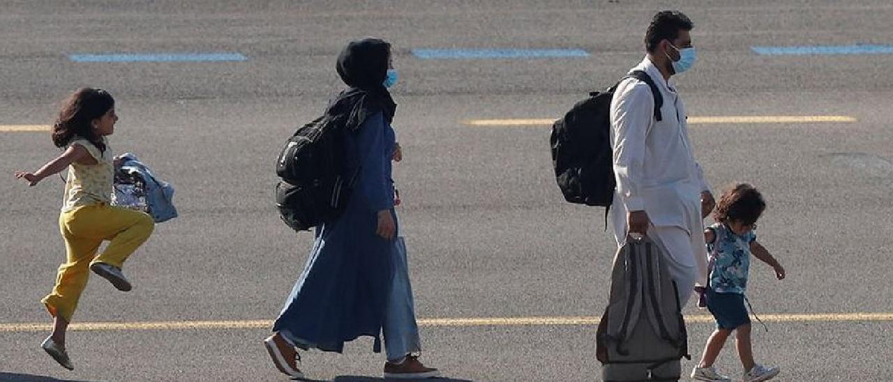 La niña afgana saltimbanqui, en la pista de un aeropuerto, junto a su familia.