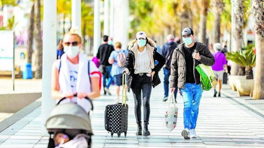 Dos personas con maletas en la primera línea de playa de la capital turística. | DAVID REVENGA