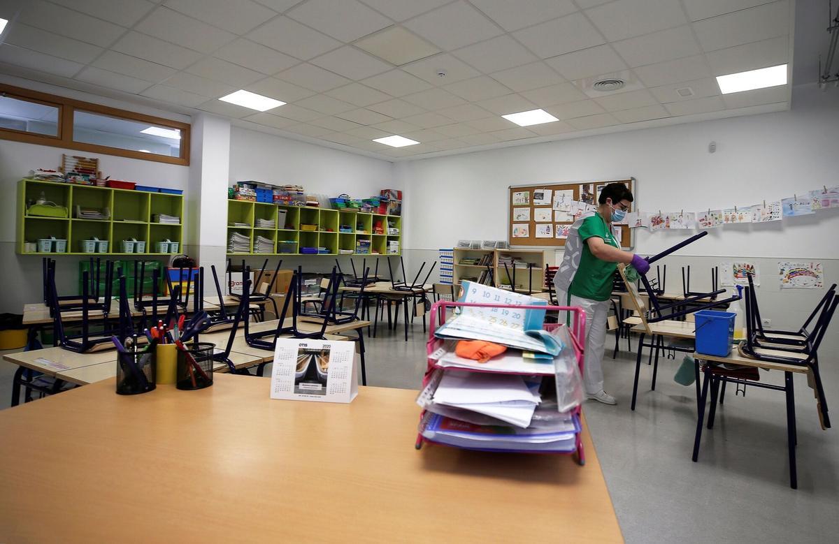 Imagen de archivo de una trabajadora limpiando el aula de un colegio.