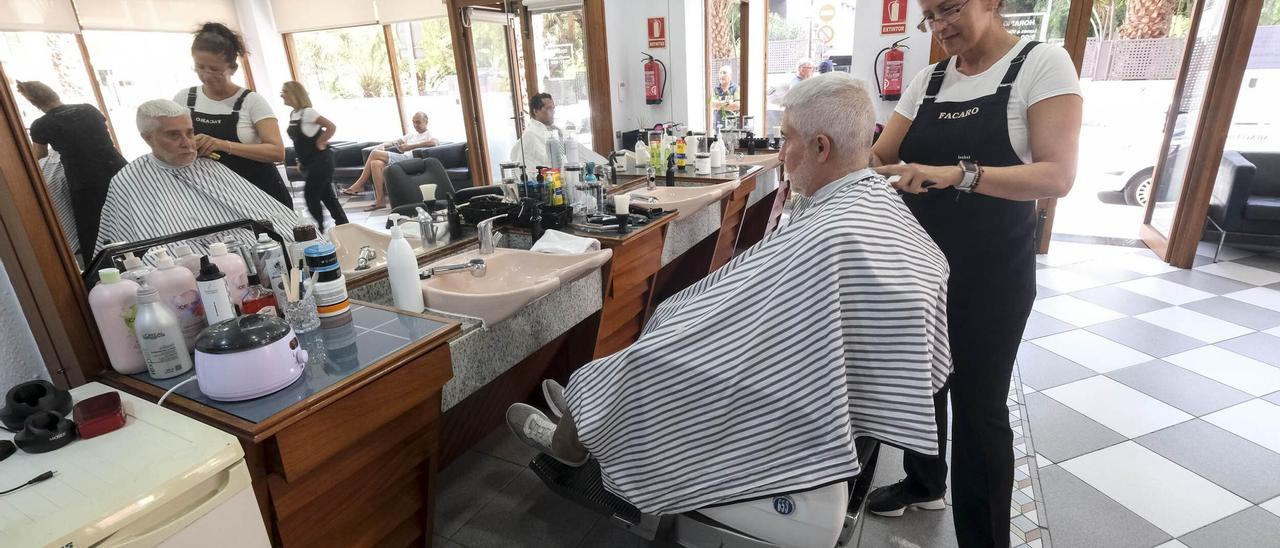 Una peluquera le corta el pelo a un cliente.