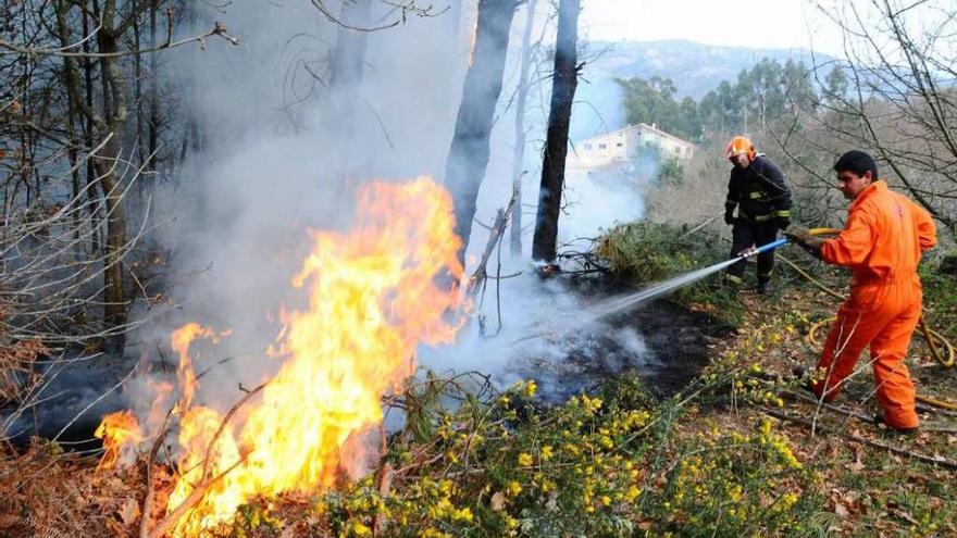 Operarios apagan un incendio en montes de Cangas provocado por una quema agrícola. // Gonzalo Núñez