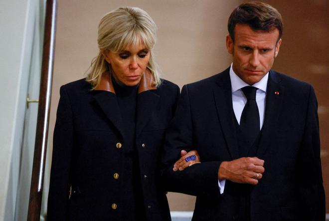 French President Emmanuel Macron (R) and First Lady Brigitte Macron (L) arrive to pay their respects to the coffin of Queen Elizabeth II, Lying in State inside Westminster Hall, at the Palace of Westminster in London on September 18, 2022. - Britain was gearing up Sunday for the momentous state funeral of Queen Elizabeth II as King Charles III prepared to host world leaders and as mourners queued for the final 24 hours left to view her coffin, lying in state in Westminster Hall at the Palace of Westminster. (Photo by JOHN SIBLEY / POOL / AFP)