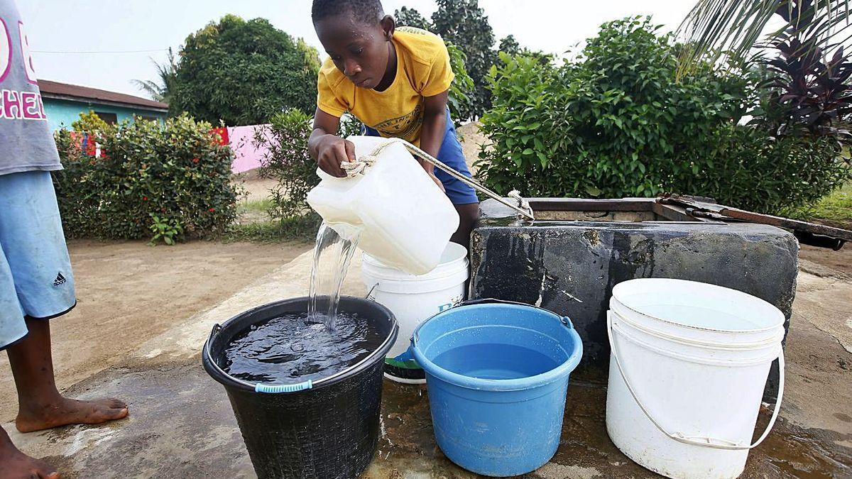 Un niño saca agua de un pozo en Monrovia