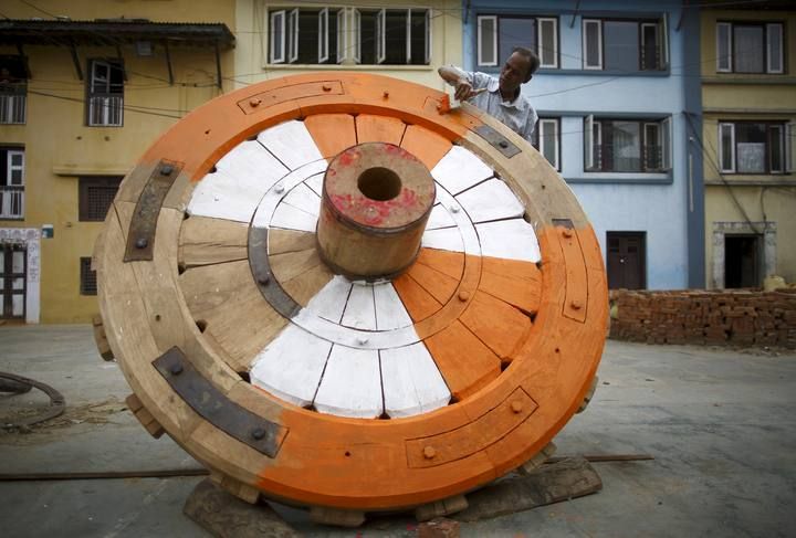 Un hombre pinta una de las ruedas de la carroza Rato Machhindranath