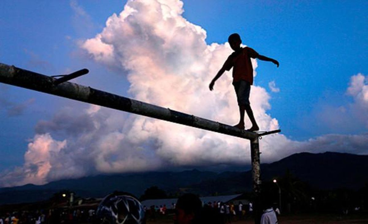 Equilibris religiosos. Un noi camina a sobre del pal d’una porteria per veure la processó que reprodueix la crucifixió de Crist, a Larantuka (Indonèsia).