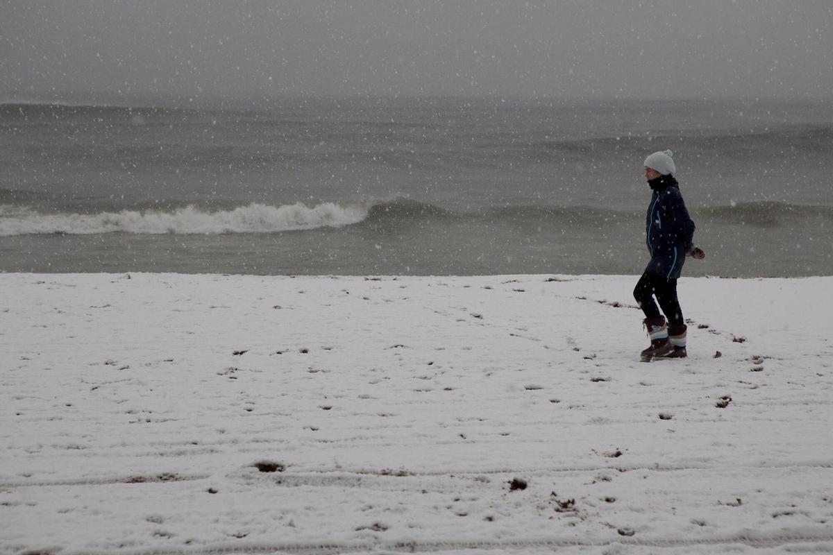 Una persona pasea por la orilla de la playa de la Barceloneta, el 8 de marzo de 2010.