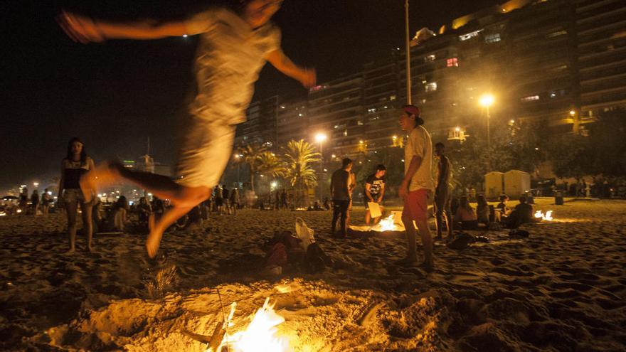 Un joven saltando hogueras en la playa en la noche del 23 de junio