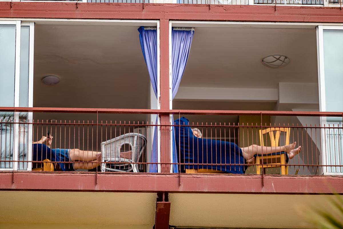 Dos personas se relajan en el balcón de unos apartamentos turísticos en Benidorm.
