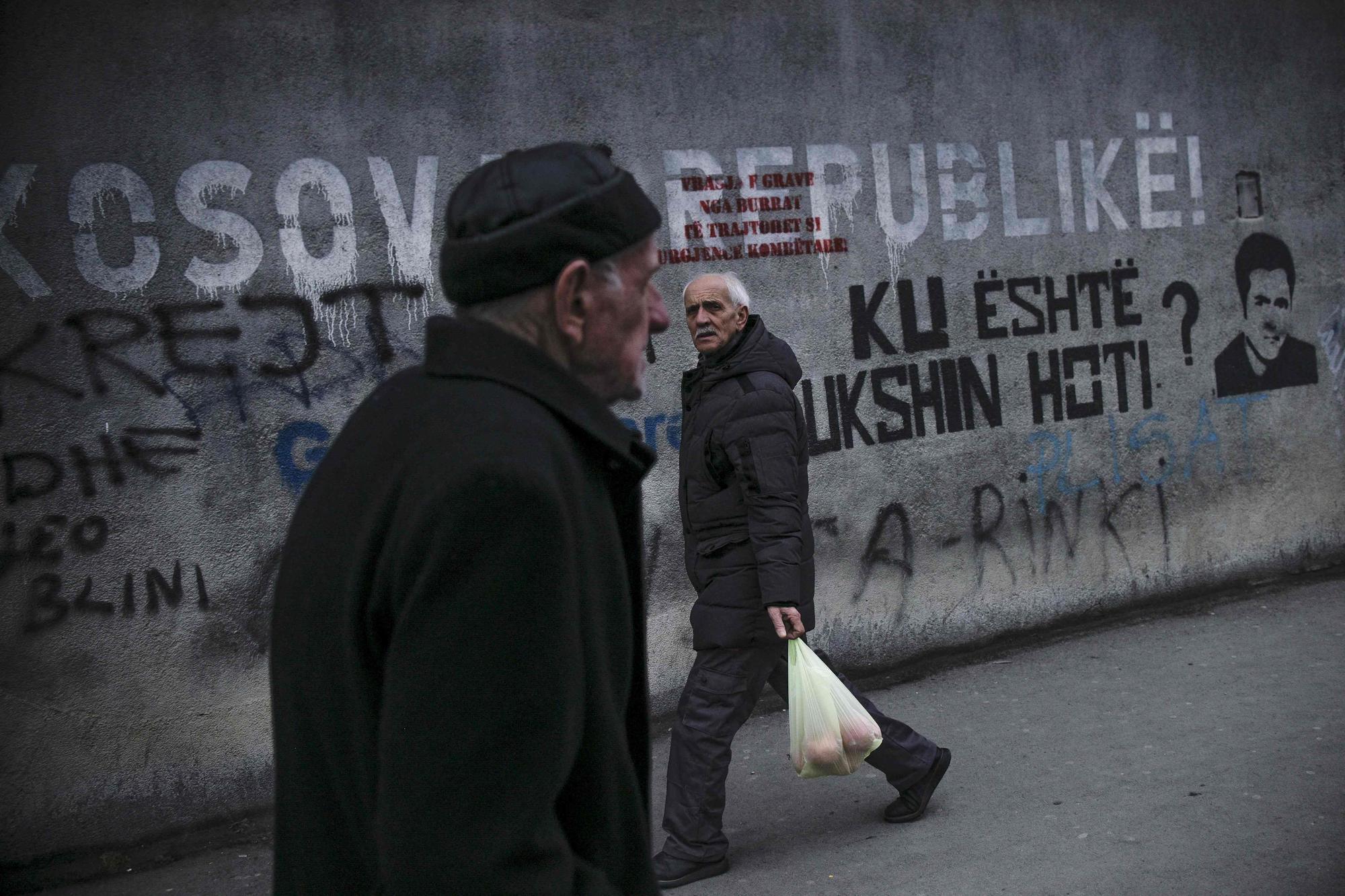 Dos albanokosovares pasan frente a un mural en el que se lee 'República de Kosovo', este lunes en Pristina.