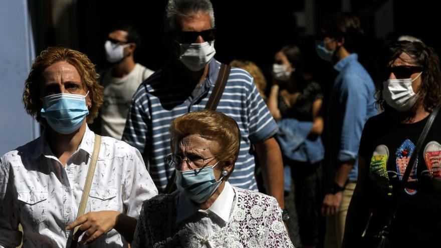 Varias personas caminan con mascarillas.