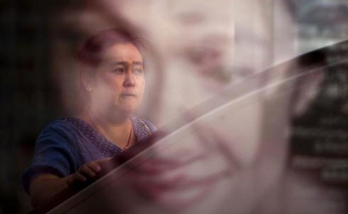 Una dona puja en una escala mecànica del metro de Pequín (Xina) mentre la seva cara es reflecteix en un cartell publicitari.