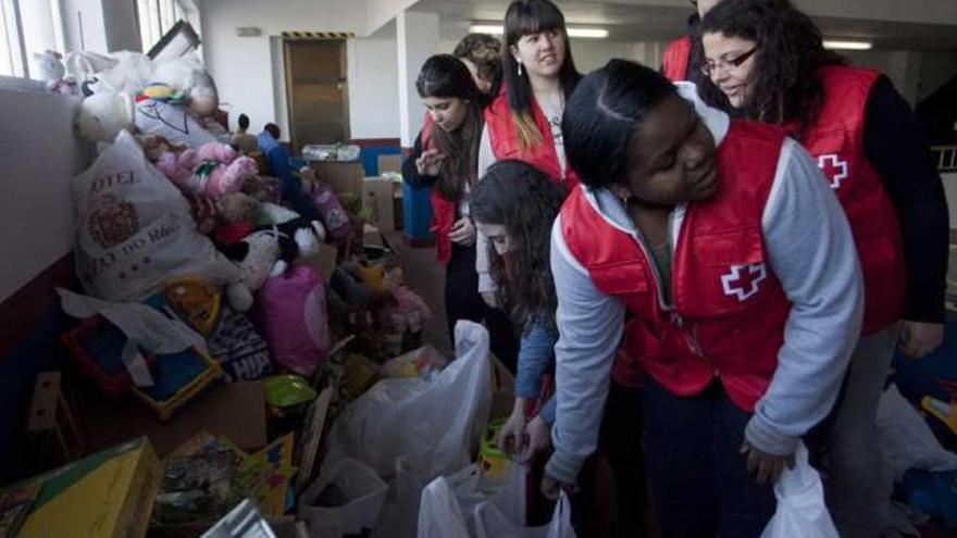 Un grupo de voluntarios de Cruz Roja Juventud, junto a la montaña de juguetes que ayer entregaron a las familias.