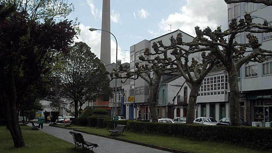 Una calle del casco urbano de As Pontes, con la chimenea de la central térmica al fondo.