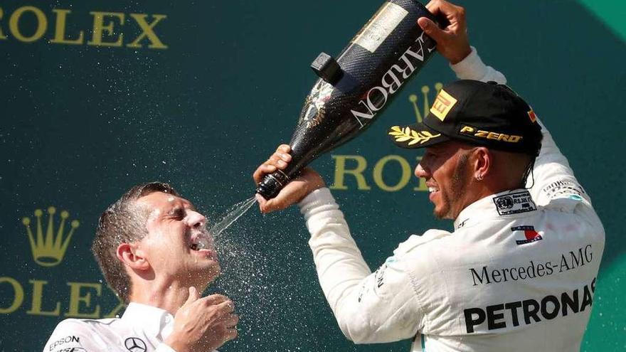 Hamilton lanza champán en la boca de su jefe de ingenieros en la ceremonia de podio. // Efe