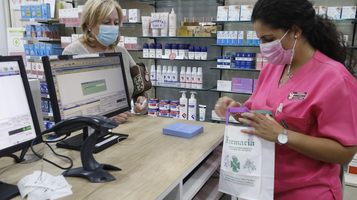 Una clienta pide un medicamento en una farmacia de la ciudad de Cáceres, ayer.