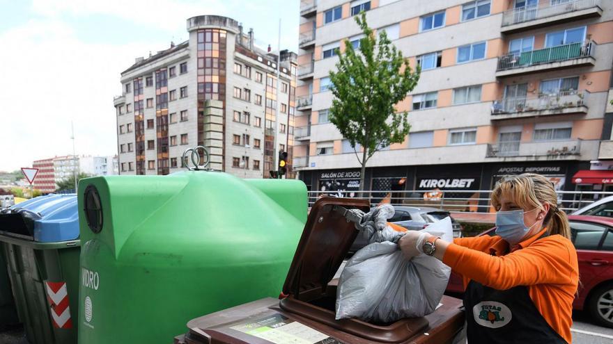 Una mujer hace uso del contenedor marrón destinado a residuos orgánicos. |   // GUSTAVO SANTOS