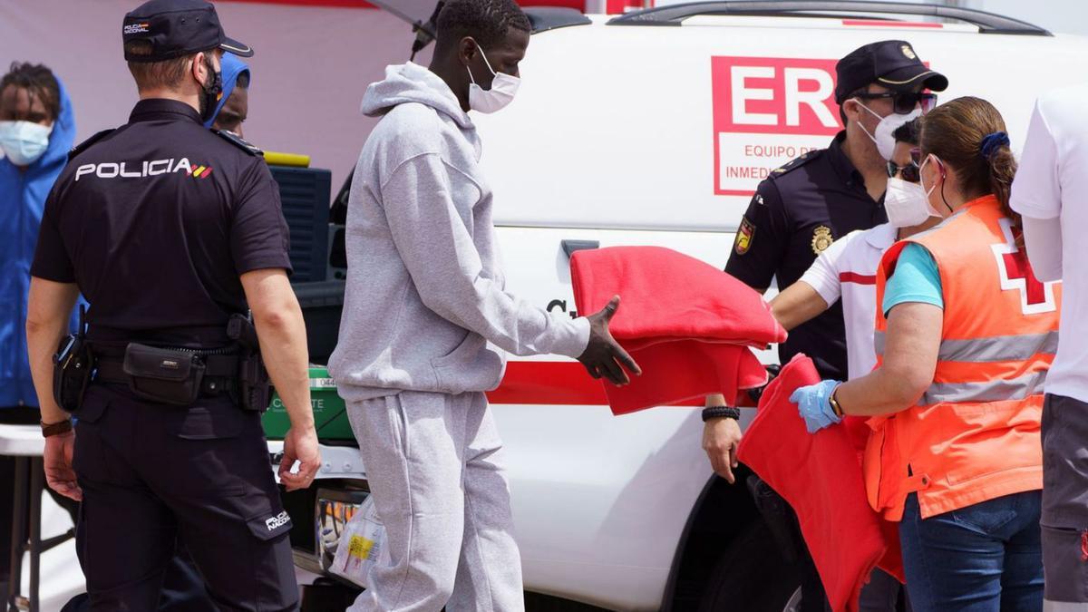 Una de las personas que llegó ayer en patera a Tenerife, recibiendo una manta del personal de Cruz Roja. | | EFE