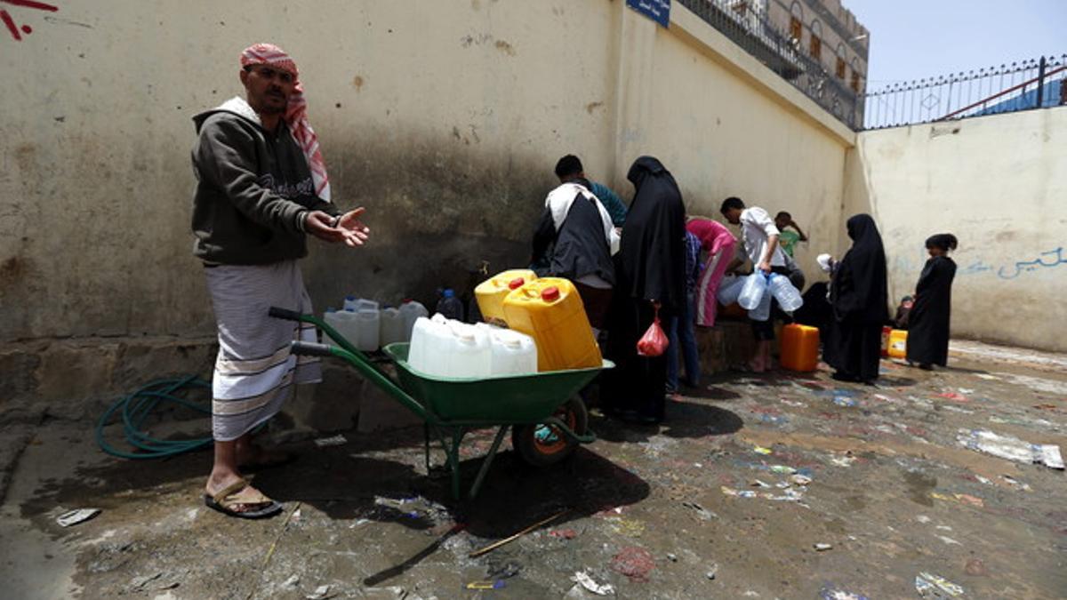 Yemenís llenan de agua potable botellas de plástico en una fuente de Saná.