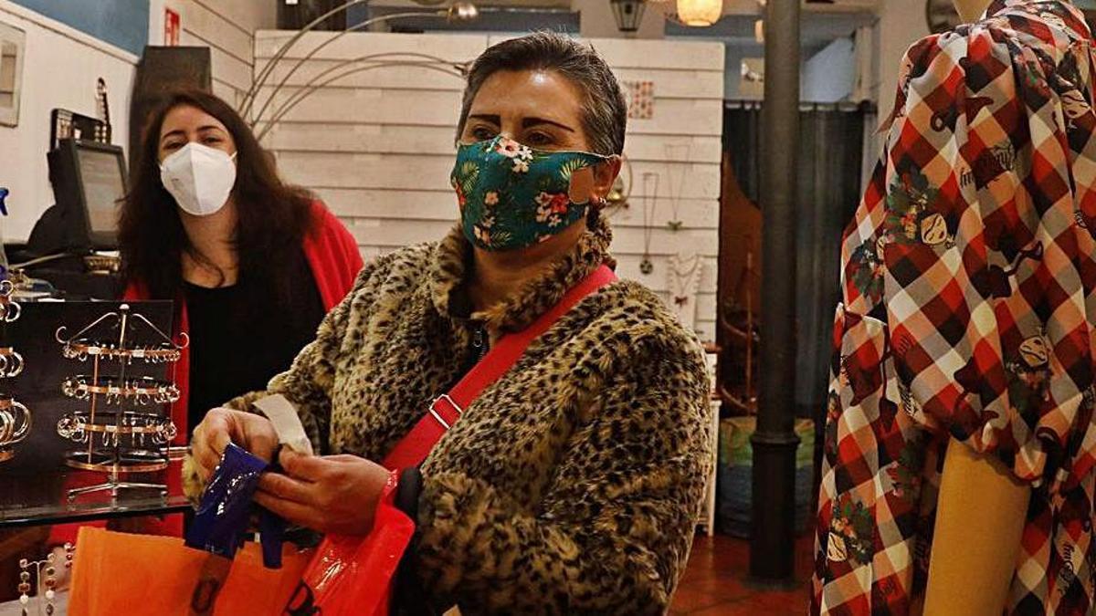 Patricia Antuña, en su negocio de Avilés, se despide de Begoña Costa, que sale del comercio con bolsas.