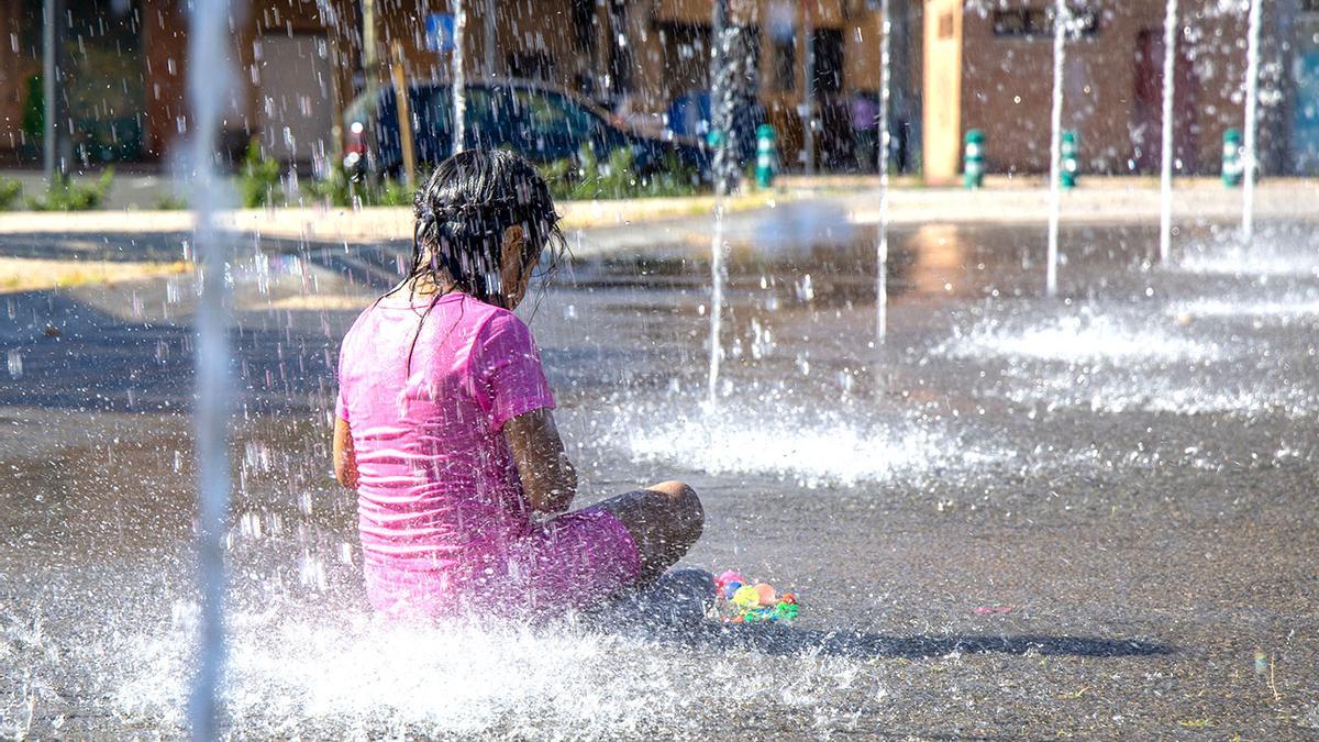 Un niño se refresca en una fuente frente al calor.