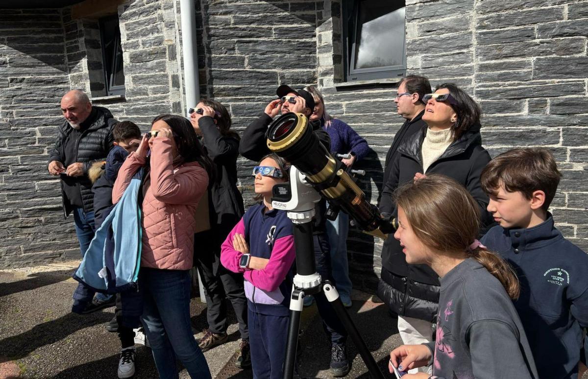 Varias personas observan el eclipse a través del telescopio y con gafas especiales, durante la actividad organizada por Allande Stars.   | D.  ÁLVAREZ / ALBERTO GOMBÁU