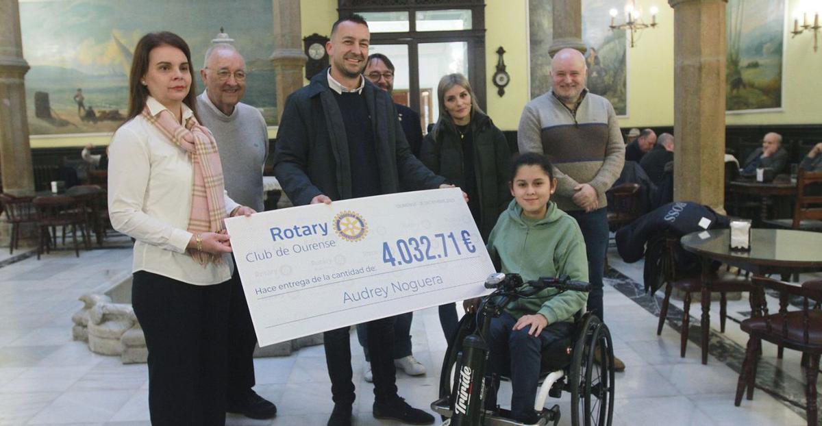 Audrey, con su madre Marta detrás, recibe el cheque de manos de Manuel Ribao, de Rotary.