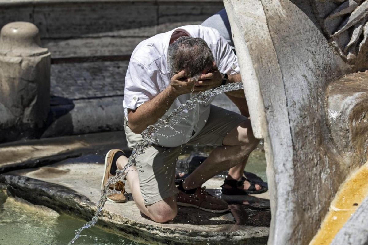 Un hombre se refresca en una fuente en Roma durante una ola de calor.