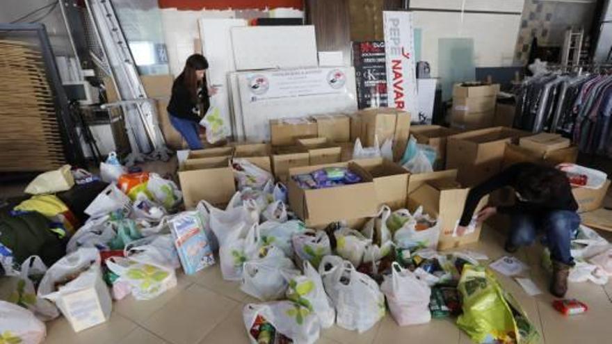 Un par de voluntarias de la plataforma de Ayuda a Personas Refugiadas Sirias de Elche preparando el material para los palés.