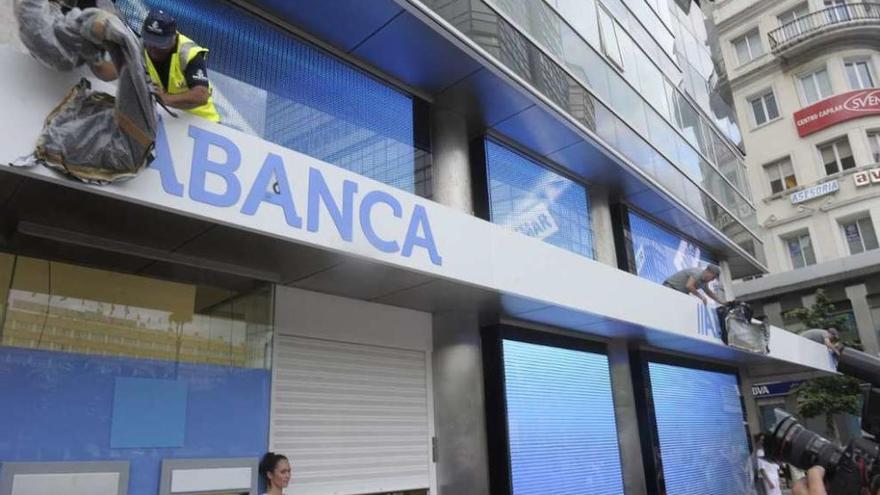Dos operarios destapan en una oficina la nueva marca de NCG tras su venta, Abanca.