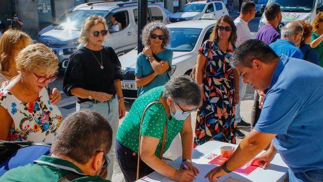 El concejal de Cambados Xurxo Charlín indica a una vecina donde puede firmar en la campaña de SOS Sanidade Pública. | // IÑAKI ABELLA